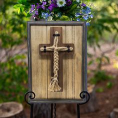 a wooden cross with flowers in the background