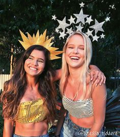 two beautiful women standing next to each other in front of trees and stars on the wall