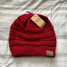 a red knitted hat with a price tag on it sitting on top of a bed