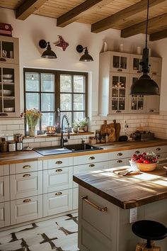 a kitchen with white cabinets and wooden counter tops next to an island in front of a window