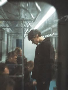 a man standing in front of a mirror on a train with other people behind him