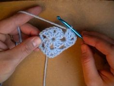 someone crocheting a piece of white yarn with a pair of scissors in their hands