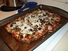 an uncooked pizza sitting on top of a metal baking pan next to a stove