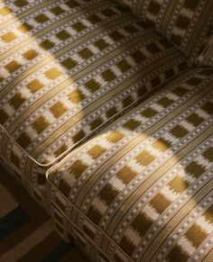 an upholstered couch with the sun shining on it's back and sides