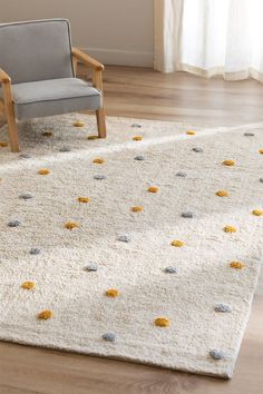 a chair sitting on top of a wooden floor next to a rug covered in yellow and gray balls