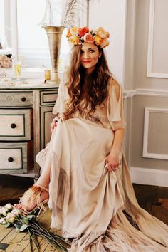 a woman is sitting on the floor with flowers in her hair and wearing a flower crown