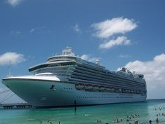 a cruise ship docked at the beach with people swimming in the water