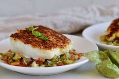 two white plates filled with food on top of a table next to lettuce