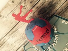 a red and blue soccer ball sitting on top of a wooden table