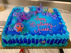 a birthday cake with blue frosting and purple decorations