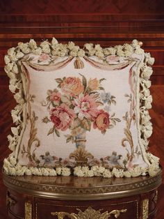 a decorative pillow with flowers on it sitting on top of a wooden table next to a wall