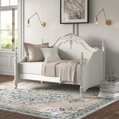 a white daybed sitting on top of a wooden floor next to a wall mounted clock