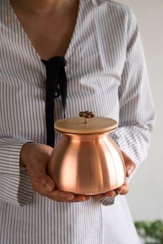 a woman holding a copper pot with a black tie on it's necktie