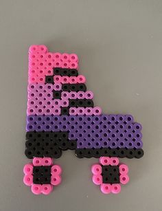 a purple, black and pink letter made out of legos on a gray surface