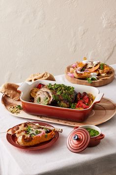 a table topped with plates and dishes filled with food next to each other on top of a white table cloth