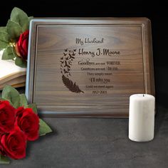 a wooden plaque with two roses and a candle on the side, next to it