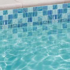 an empty swimming pool with blue tiles on the wall and water reflecting off it's surface