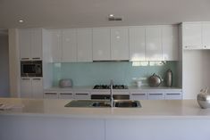 a white kitchen with stainless steel appliances and counter tops is seen in this image from the front view