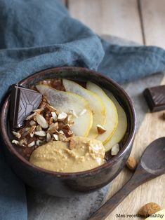 a bowl filled with fruit and nuts on top of a wooden cutting board next to a spoon