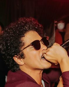 a man with sunglasses on singing into a microphone