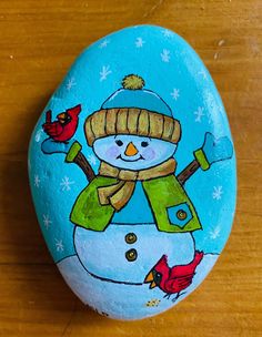 a painted rock with a snowman and birds on it