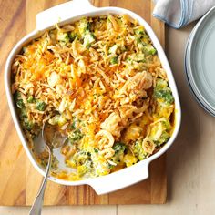 a casserole dish with chicken and broccoli in it on a cutting board