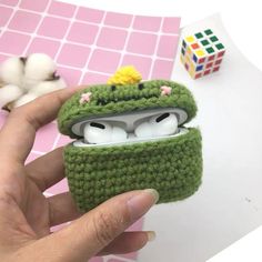 a hand holding an earphone case made to look like a frog