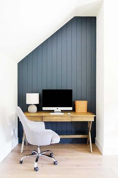 a desk with a computer on top of it in front of a slanted wall