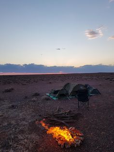 a campfire in the middle of nowhere with a tent on it's side