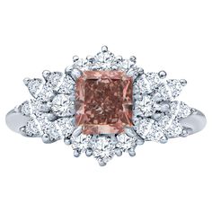 a fancy ring with an orange diamond surrounded by smaller diamonds and white gold, on a white background