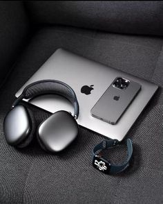 an apple laptop computer sitting on top of a couch next to headphones and ear buds