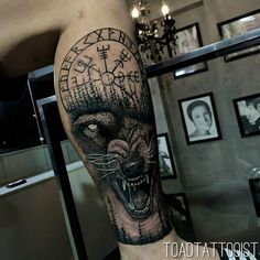 a man's leg with a black and grey tattoo on it, depicting an evil wolf