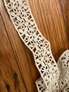 a piece of white crocheted fabric sitting on top of a wooden floor