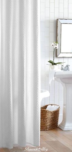 a white shower curtain in a bathroom next to a sink