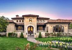 this is an image of a beautiful house in the evening time with flowers on the front lawn