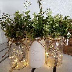 two mason jar vases with flowers and fairy lights are sitting on a table next to each other