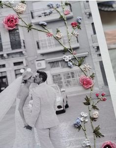 a wedding photo with flowers on it and a couple kissing in front of a building