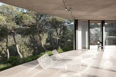 a white bench sitting on top of a cement floor next to a tree covered hillside