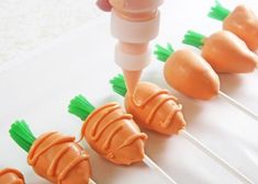 carrots being dipped with orange icing on toothpicks in order to be eaten