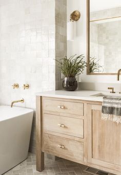 a bathroom with a tub, sink and mirror