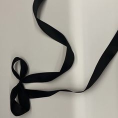 a black ribbon is tied to a white wall with an object in the corner behind it