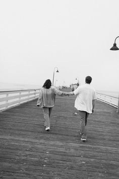 two people walking down a pier holding hands