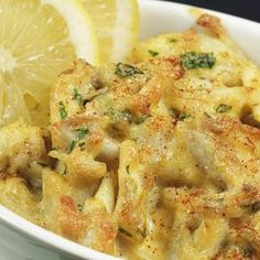 a white bowl filled with pasta and lemon wedges