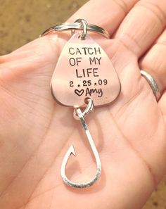 a hand holding a metal keychain that says catch of my life