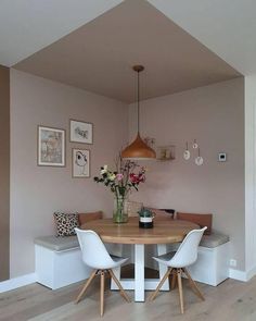 a dining room table with two chairs and a bench in front of it, along with pictures on the wall