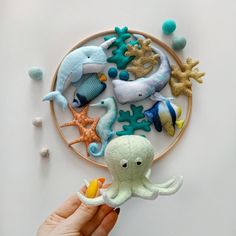 a person holding an octopus toy in front of a wall hanging with sea animals on it