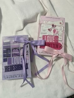 two books with ribbons tied to them on top of a white bed sheet, next to each other