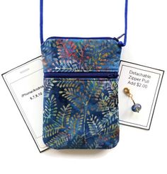 a small blue purse sitting on top of a table next to two tags and a pair of earrings