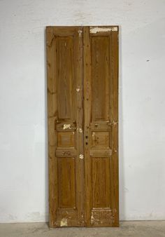 an old pair of wooden doors sitting on top of a cement floor next to a white wall