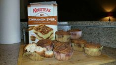 several muffins on a cutting board next to a carton of cinnamon swirl